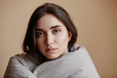 Battaniyeye sarılı, kameraya bakıp, boşluğu kopyalayan depresif genç kadının en az portresi.