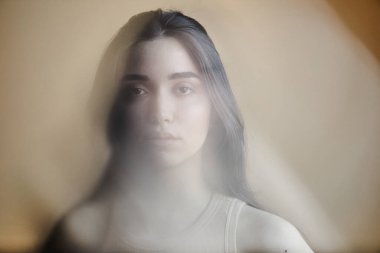 Zihinsel sorunlarla boğuşan ve kameraya bakan genç bir kadının bulanık portresi.