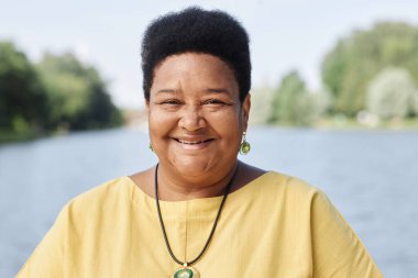 Açık havada kameraya gülümseyen yaşlı siyahi bir kadının gizli portresi.