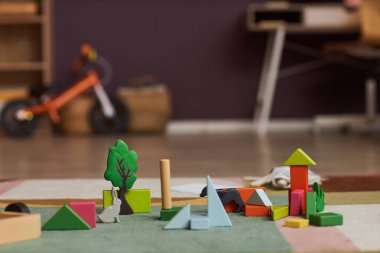 Oyun odasındaki renkli halıya ahşap oyuncakları ve tuğlaları kapatın, boşluğu kopyalayın
