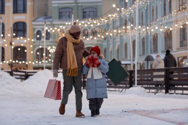 Baba ve çocuğun mutlu bir portresi. Kışın kameraya doğru yürüyor ve alışveriş torbaları tutuyor. Kopya alanı.