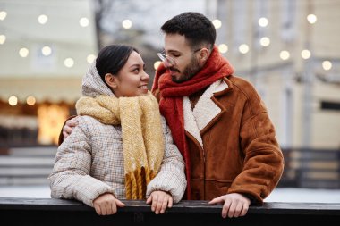 Buz pateni pistinde eğlenen ve birbirlerine sevgiyle bakan genç çiftin portresi.