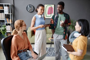 Modern ofiste fikir alışverişinde bulunan çok ırklı genç iş adamları.