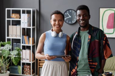 Ofiste kameraya gülümseyen iki Afro-Amerikan profesyonelin belden yukarı portresi.