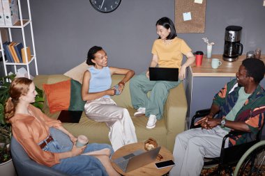 Ofis salonunda birden fazla etnik gruptan genç profesyoneller toplanıyor.