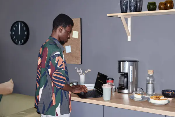 stock image Side view portrait of young Black man making drinks at coffee station in office