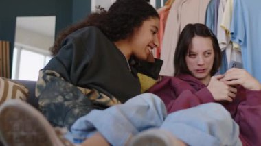 Rahat bir dairede rahat rahat kanepede oturmuş dedikodu yapan gündelik giysili iki genç kızın orta boy fotoğrafı. Kızlardan biri beyin felci geçiriyor.