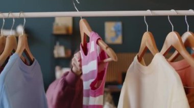 Kafkasyalı, serebral felçli genç bir kızın rahat yatak odasında elbise askılığında dikilip giyeceği kıyafeti seçerken orta boy bir fotoğrafı.