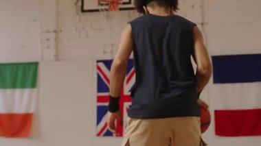 Çift ırklı erkek basketbolcunun kapalı alanda basketbol oynaması ve basket atmada serbest atış yapması.