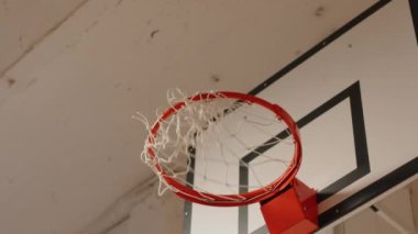 Tanımlanamayan basketbolcuların yavaş yavaş sahada antrenman yaparken topu potaya atması.