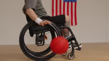 Tanımlanamayan tekerlekli sandalyeli bir adamın kapalı alanda tek başına basketbol oynarken salyalarını akıtırken çekilen yan görüş yavaş çekimi.