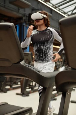 VR kulaklık takan sporcu bir gencin dikey portresi. Fütüristik antrenman sırasında spor salonunda koşu bandında koşuyor.