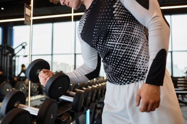 Salon fotokopi salonunda ağırlık antrenmanı sırasında elinde ağır dambıl tutan kaslı adamın yan görüntüsü.