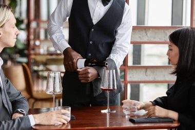 Lüks restoranda çifte kırmızı şarap sunan garsonu kapatın.