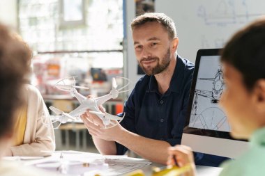 Gülümseyen öğretmen grup pf çocuklarının nasıl çalıştığını anlatıyor.