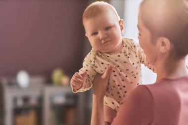Genç annenin güneş ışığı parıltısında sevimli bir bebekle oynadığı yakın plan, kopyalama alanı.