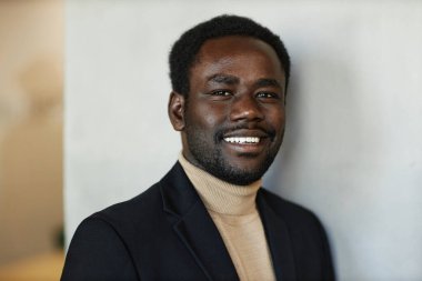 Takım elbiseli neşeli genç siyahi adam kameraya bakıyor. Yakın çekim, uzay kopyası.