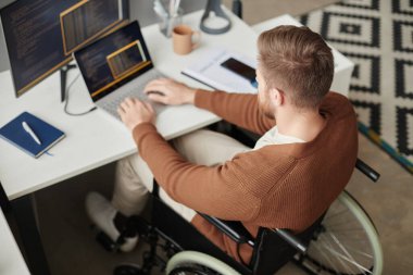 İşyerinde kod yazan bilgisayar programcısı olarak engelli bir gencin yüksek açılı görüntüsü