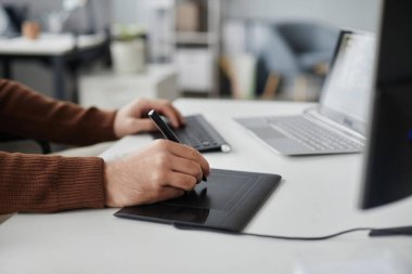 Ofiste fotoğraf ya da video düzenlerken kalem tableti kullanan tanınmayan bir adamın kenar görüntüsü, yer kopyala