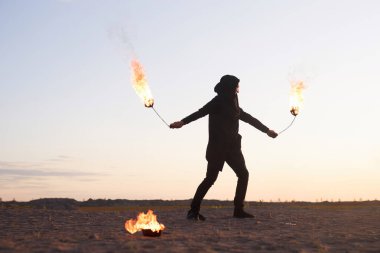 Ateş gösterisi sırasında ateş poi 'si ile dans eden genç bir adamın yan görünüm portresi. Doğada gösteri, uzay kopyası.