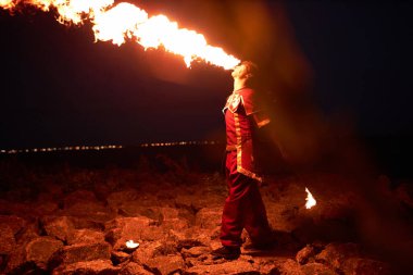 Ateş püskürten genç adamın yan görünüm portresi. Geceleri dışarıda gösteri yapıyor, uzayı kopyalıyor.