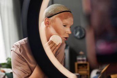 Sosyal medya için makyaj kursları çeken genç bir adamın yan görünüm portresi, halka ışığı, kopyalama alanı