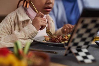 Küçük siyahi kızın masada yemek yiyip internetten fotokopi çekilen videoları izlediği bir sahne.