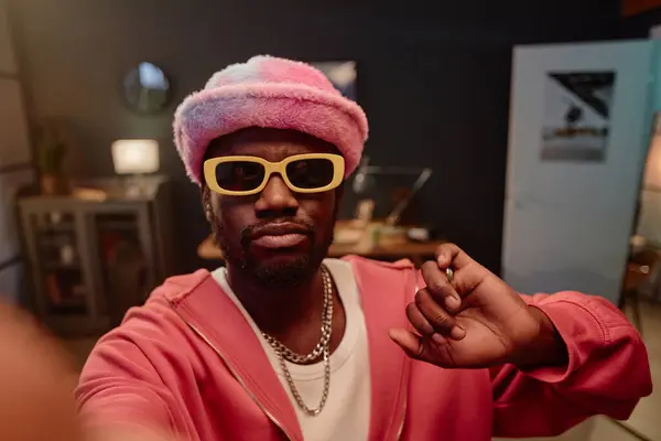 stock image POV of Black man taking selfie photo or recording video for social media while wearing pink trendy outfit copy space