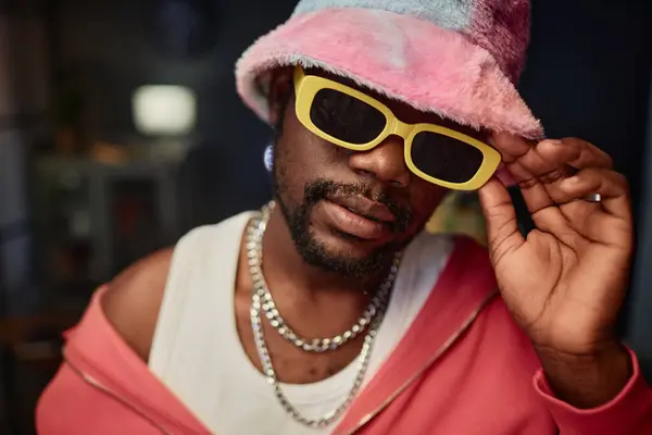 stock image Close up portrait of Black young man wearing fuzzy bucket hat and trendy sunglasses looking at camera indoors