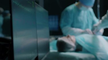 Ameliyat sırasında hastanın durumunu gösteren iki hayati monitör ameliyat odasında tek kullanımlık mavi önlüklü iki doktor tarafından gerçekleştirildi.