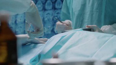 Alet ve atık için metal tepsiyi tutan asistanın ameliyat odasında çalışırken tanınmayan bir cerrahın mükemmel dikiş attığı görüntüler.