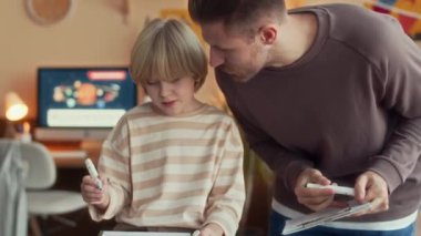 Kafkasyalı bir gencin evde babasıyla resim çizerken, yumuşak bir kanepede güzel bir dairede yan yana otururken.