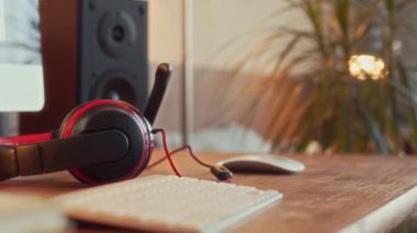 Hiçbir insan, genç yatak odasındaki hoparlörlü bilgisayar monitörünün yanında, beyaz kablosuz klavyeye ve ahşap masadaki siyah ve kırmızı oyun kulaklıklarına odaklanmaz.