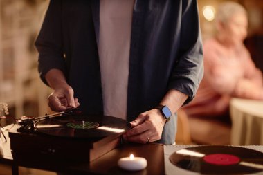 Tanımlanamayan adamın ön görüntüsü vinil kayıt cihazı kuruyor ve ambians kopyalama alanı olan retro müziğin tadını çıkarıyor.