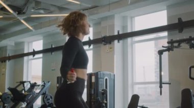 Spor salonunda kardiyo eğitimi sırasında siyah aktif giyimli, ip atlayan beyaz kadın sporcuları yavaş yavaş aşağı indirin.
