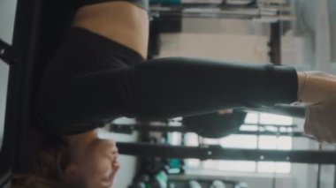 Beyzbol antrenmanında ağırlık kaldırırken ve yedek kulübesinde uzanan güçlü beyaz kadın sporcunun dikey yan görüntüsü