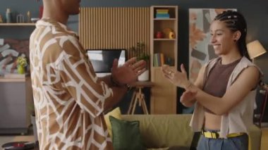 Canlı giysiler içinde dans eden, modaya uygun tasarlanmış dairede dans eden genç, çılgın, çift cinsiyetli bir çift.