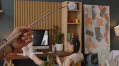 Modern bir dairede bacakları masanın üstünde oturan melez bir kız. Oyuncu erkek arkadaşı da onu pp Duster 'la taciz ediyor.