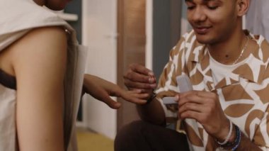 Melez genç adam evlenme teklif ediyor ve evde kız arkadaşının parmağına nişan yüzüğü takıyor.