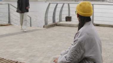 İlkbaharda su kenarında sevgili kız arkadaşına evlenme teklif eden heyecanlı bir çift ırklı genç.