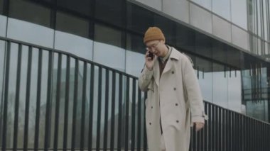 Şehirdeki modern cam binalarda yürürken cep telefonuyla konuşan kendine güvenen Asyalı genç adamın yavaş yavaş izini sürüyorum.