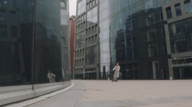 Asyalı adamın modern bölgede cam ofis binalarıyla e-scooter sürerken ve yaşam tarzı video blogu çekerken UGC fotoğrafı.
