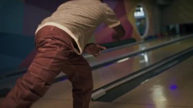 Afro-Amerikan bir adamın bowling topunu fırlatıp, etnik çeşitlilikteki arkadaşlarına beşlik çakarken ve birlikte takılıp eğlenirken elde çekilmiş bir fotoğrafı.