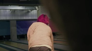 Renkli pembe saçlı Asyalı çocuk hafta sonları çok ırklı arkadaşlarıyla bowling oynuyor.