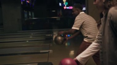 Orta halli, çoklu etnik çeşitlilikte genç bir çiftin bowling sahalarına bowling topu atıp birlikte oynarken gülmeye başladıkları bir sahne.