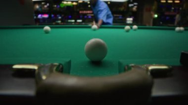 Pub 'da oynanan bilardo topunu hedef alan konsantre olmuş genç siyahi bir adamın...