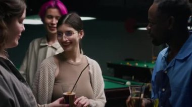Dört farklı gencin bilardo masasında çifte randevu sırasında aperatiflerle ve kokteyllerle sohbet ettiği orta boy bir fotoğraf.