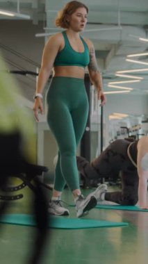 İki genç çoklu etnik çeşitlilikte ve beden ölçülerinde kadının yoga minderleri üzerinde denge kurma çalışması yaparken spor salonunda kadın antrenörle fitness antrenmanı yaparken çekilen sahneler.