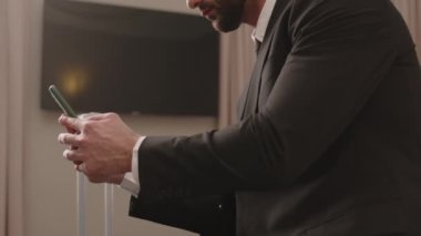 Orta ölçekli bir Orta Doğulu erkek girişimcinin otel odasındaki yumuşak yatakta otururken iş seyahatinde telefon görüşmesi yapmasını çek.