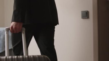 Orta Doğulu iyi görünümlü bir işadamının bavulunu otel odasında taşıdığı ve sonra da rahat bir şekilde cep telefonuyla yatağa uzandığı arka plan görüntüsü.